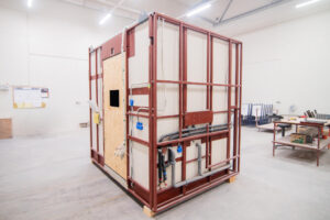 Prefabrykowany moduł łazienkowy z drzwiami z OSB i poprowadzoną instalacją pod podłogą.